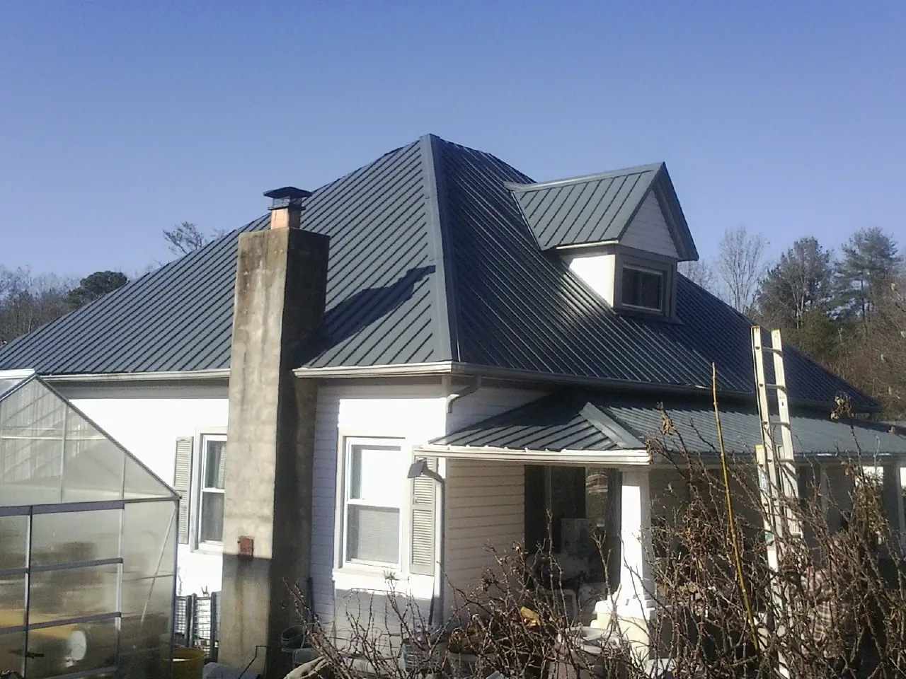 Dark blue standing seam metal roof on a white farmhouse with dormer — Slate & Tile Roof Repair by Roofing Brothers in Wahoo