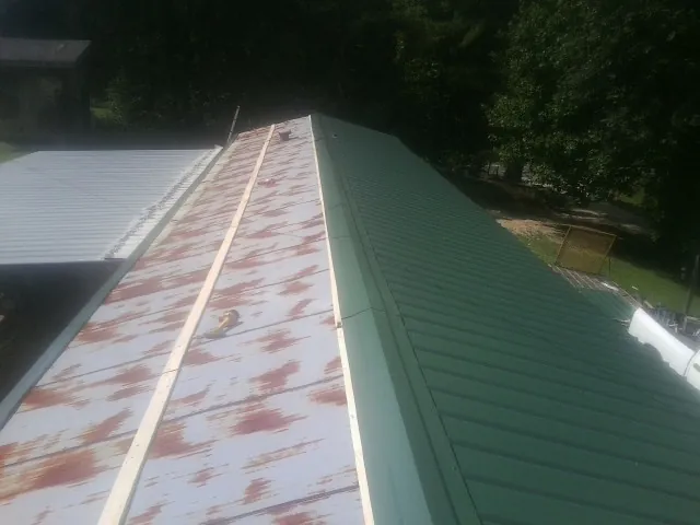 Old rusted panels beside newly installed green metal roofing — Wind Damage Roof Repair by Roofing Brothers in Wahoo