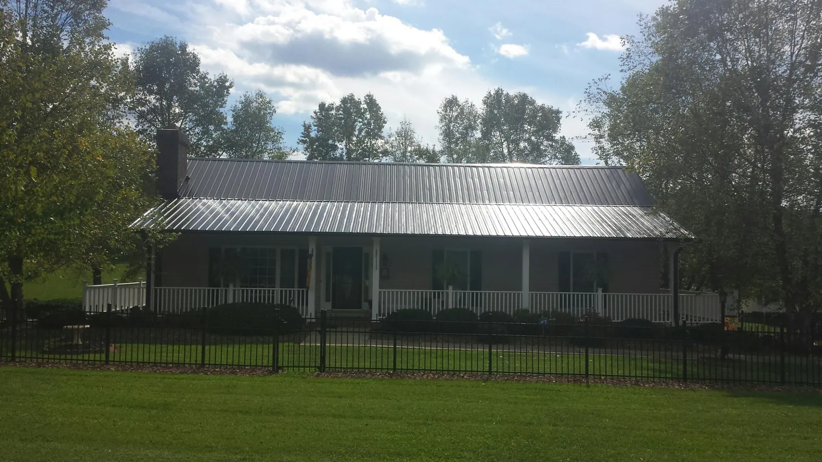 Gray metal roof on a brick ranch with a full width front porch — Gutter Guard Installation work by our crew in Wahoo