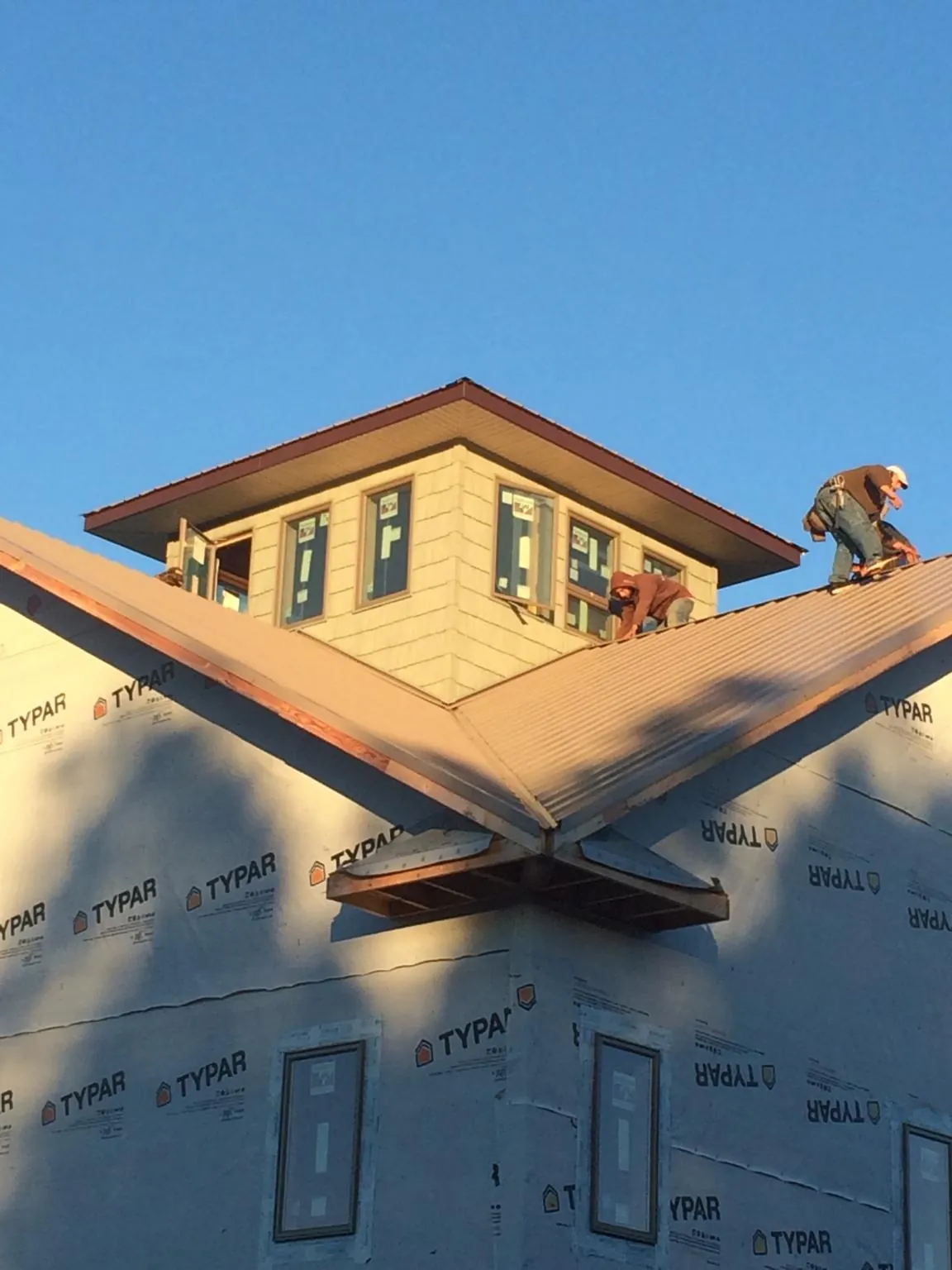 Roofers working around a rooftop cupola on a new metal roof at sunset — Roof Waterproofing in Wahoo by Roofing Brothers